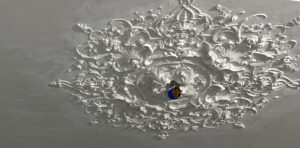 Op maat gemaakt gepleisterd plafond nadert de voltooiing met een gemonteerde kroonlijst en een sierlijk plafond in het midden tijdens de laatste installatiefasen in Amsterdam